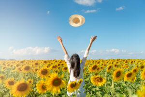 Woman raising arms in joy in a field of sunflowers