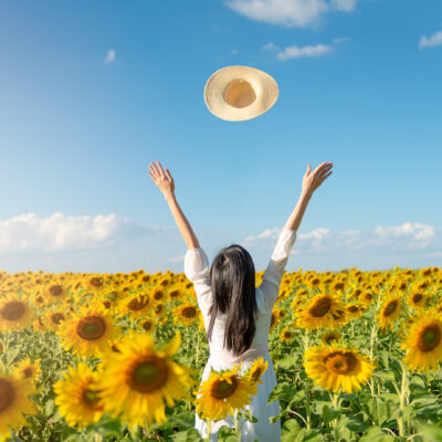 Woman raising arms in joy in a field of sunflowers